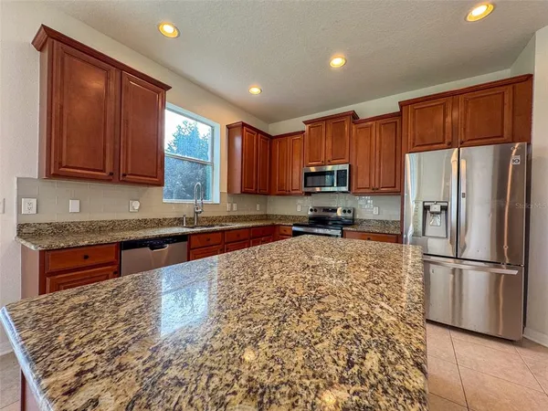 a kitchen with granite countertop wooden cabinets a refrigerator and a sink