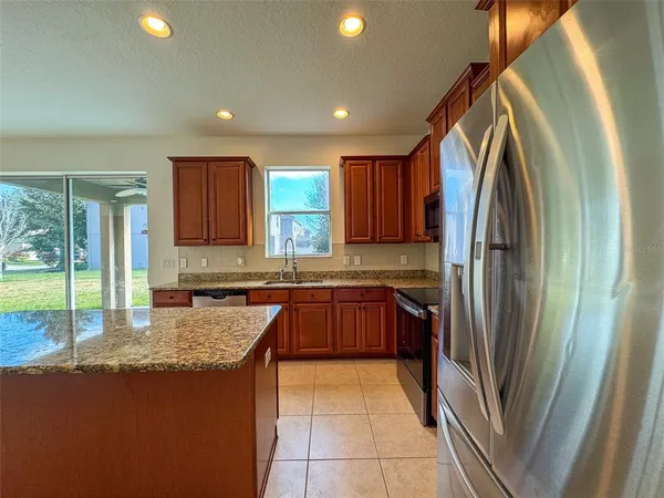 a kitchen with stainless steel appliances granite countertop a refrigerator a sink and a stove
