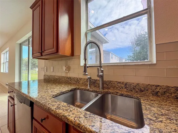 a kitchen with a granite countertop sink and natural light