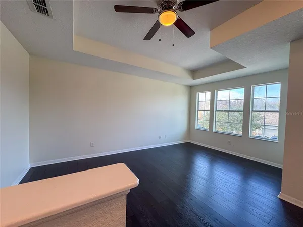 an empty room with wooden floor and windows