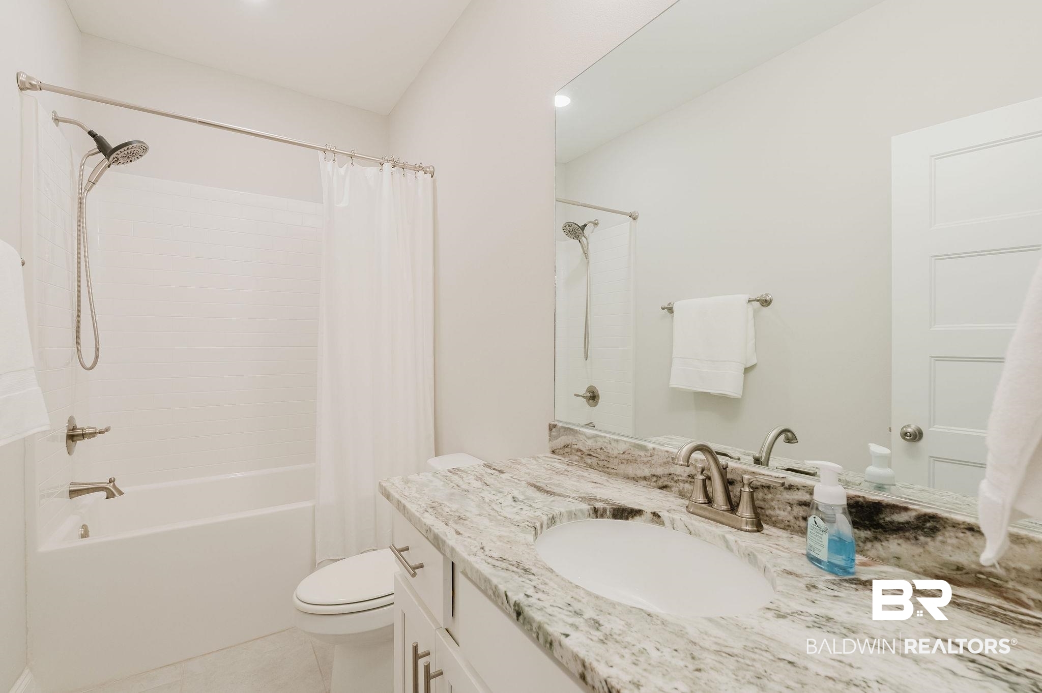 7872 Calverton Street Foley, AL 36535 - Photo 12 of 76 Bathroom featuring a white tub and shower combination with brushed nickel fixtures, a single vanity with a patterned stone countertop, an integrated sink, and a large wall-mounted mirror