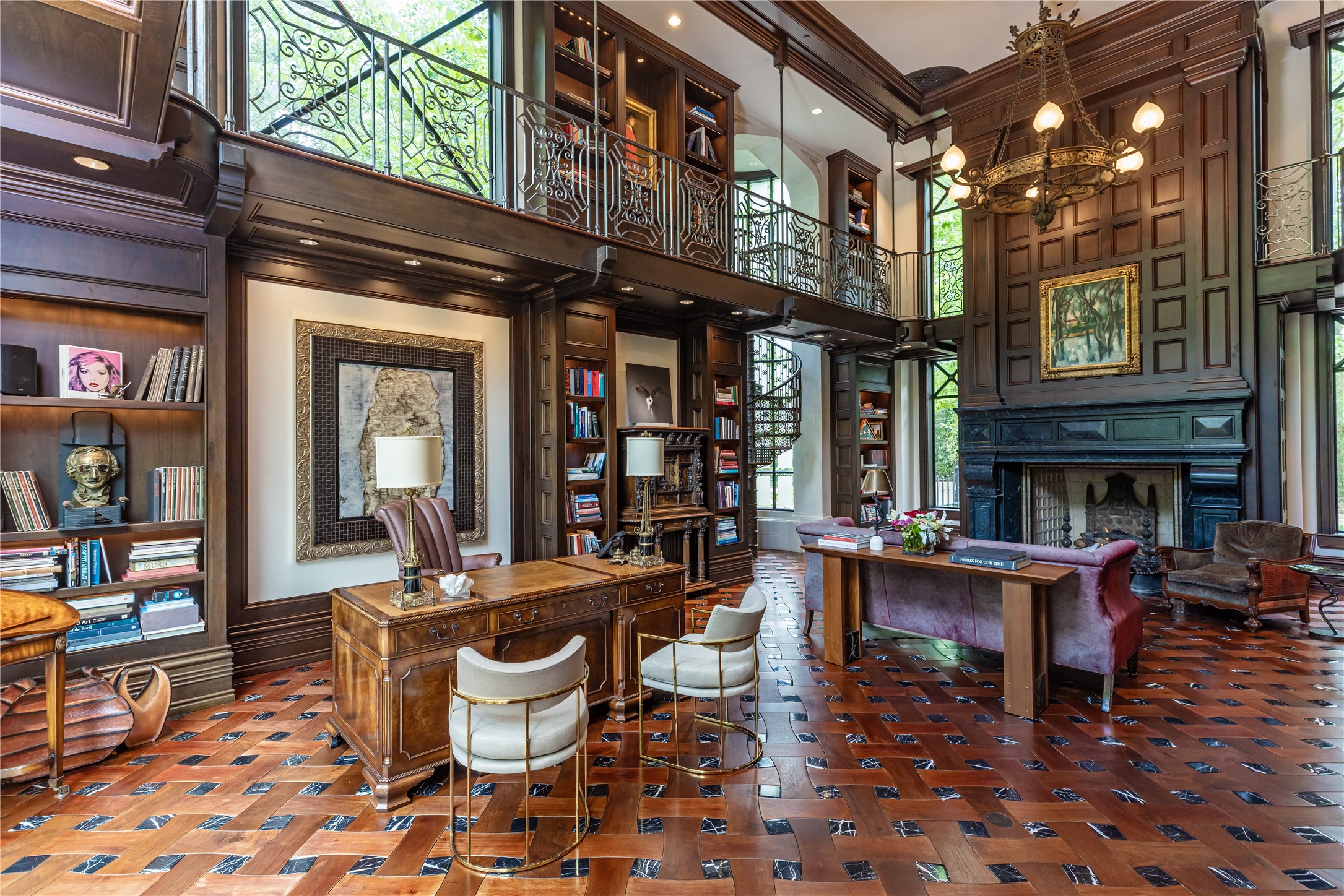 107 Timberwilde Lane Houston, TX 77024 - Photo 16 of 40 From another vantage, the library reveals its dramatic scale and artistry. The soaring two-story gallery is lined with intricate ironwork and rich custom millwork, anchored by a monumental fireplace. An imported spiral staircase curves upward with sculptural elegance, while sweeping walls of glass flood the room with light and frame views of the estate’s manicured grounds. A perfect balance of sophistication and comfort, this space embodies both architectural pedigree and livable luxury.
