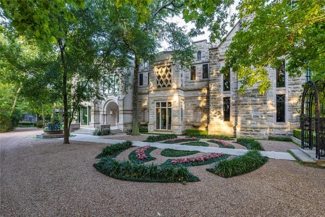 a view of a brick house with a big yard and large tree and plants