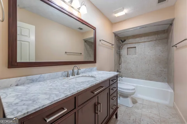 a bathroom with a granite countertop sink a toilet and bathtub