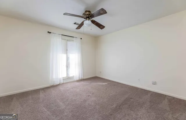 an empty room with a ceiling fan and window