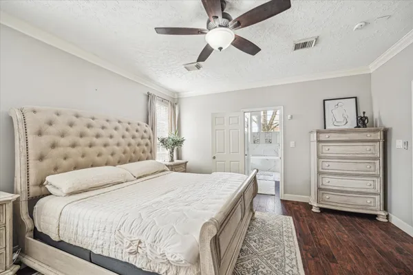 a bedroom with a large bed and a chandelier fan