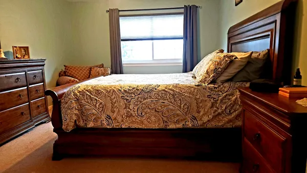 a living room with a bed and a dresser next to a window