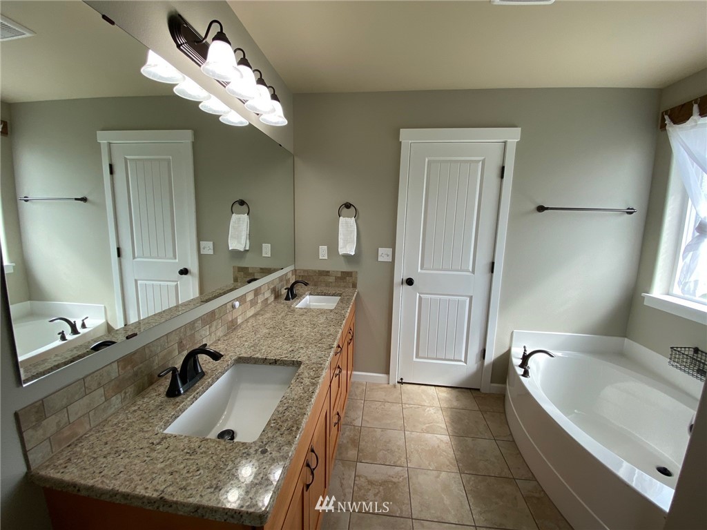9235 179th Trail Southwest Rochester, WA 98579 - Photo 20 of 38 a bathroom with a granite countertop sink a large mirror and a bathtub