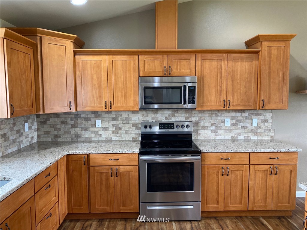 9235 179th Trail Southwest Rochester, WA 98579 - Photo 6 of 38 a kitchen with granite countertop a stove and a microwave