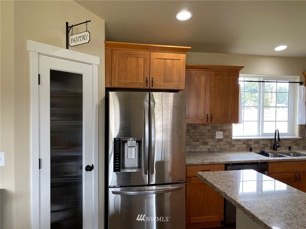 9235 179th Trail Southwest Rochester, WA 98579 - Photo 7 of 38 a kitchen with granite countertop a refrigerator and a sink