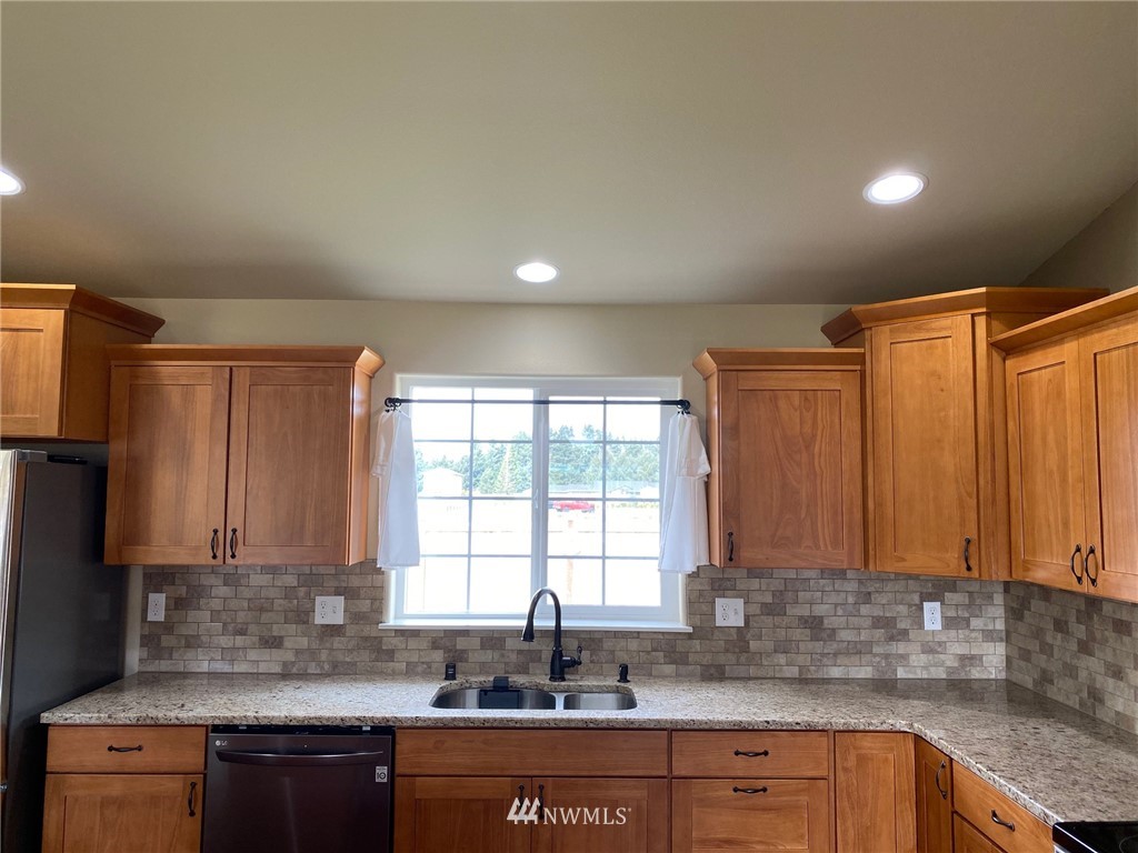 9235 179th Trail Southwest Rochester, WA 98579 - Photo 8 of 38 a kitchen with stainless steel appliances granite countertop a sink a refrigerator and a granite counter tops