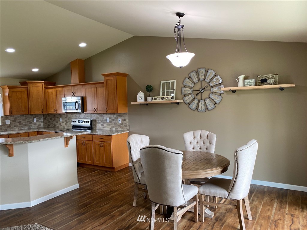 9235 179th Trail Southwest Rochester, WA 98579 - Photo 9 of 38 a dining room with wooden floor a chandelier a wooden table and chairs