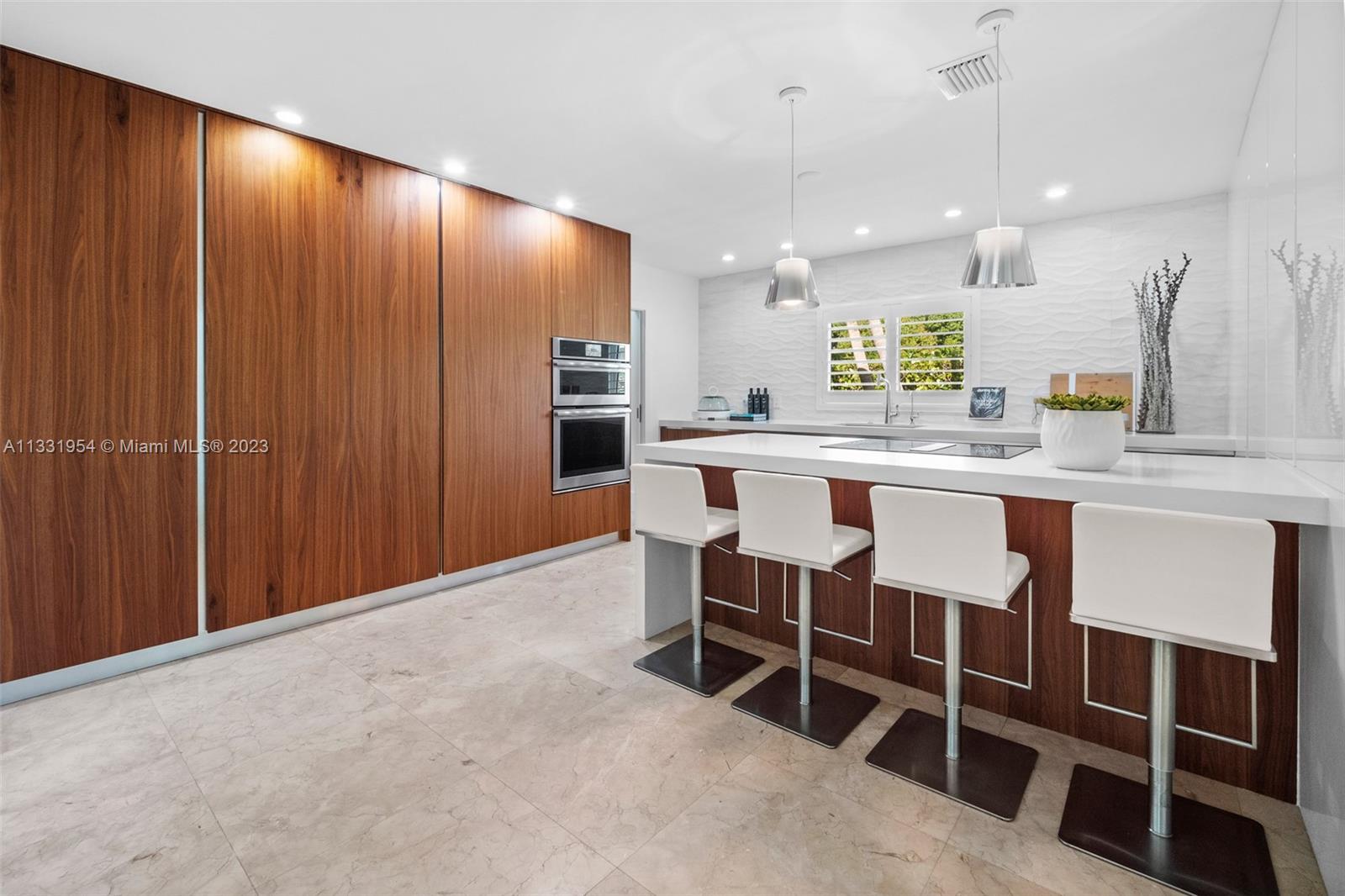 12050 Moss Ranch Road Pinecrest, FL 33156 - Photo 11 of 45 a kitchen with kitchen island a dining table chairs cabinets and stainless steel appliances