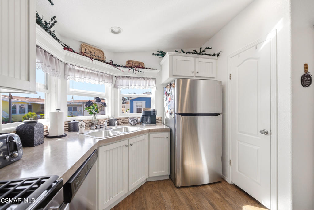 2167 Cardinal Avenue Oxnard, CA 93033 - Photo 19 of 36 a kitchen with stainless steel appliances a refrigerator a sink dishwasher a stove and white cabinets with wooden floor