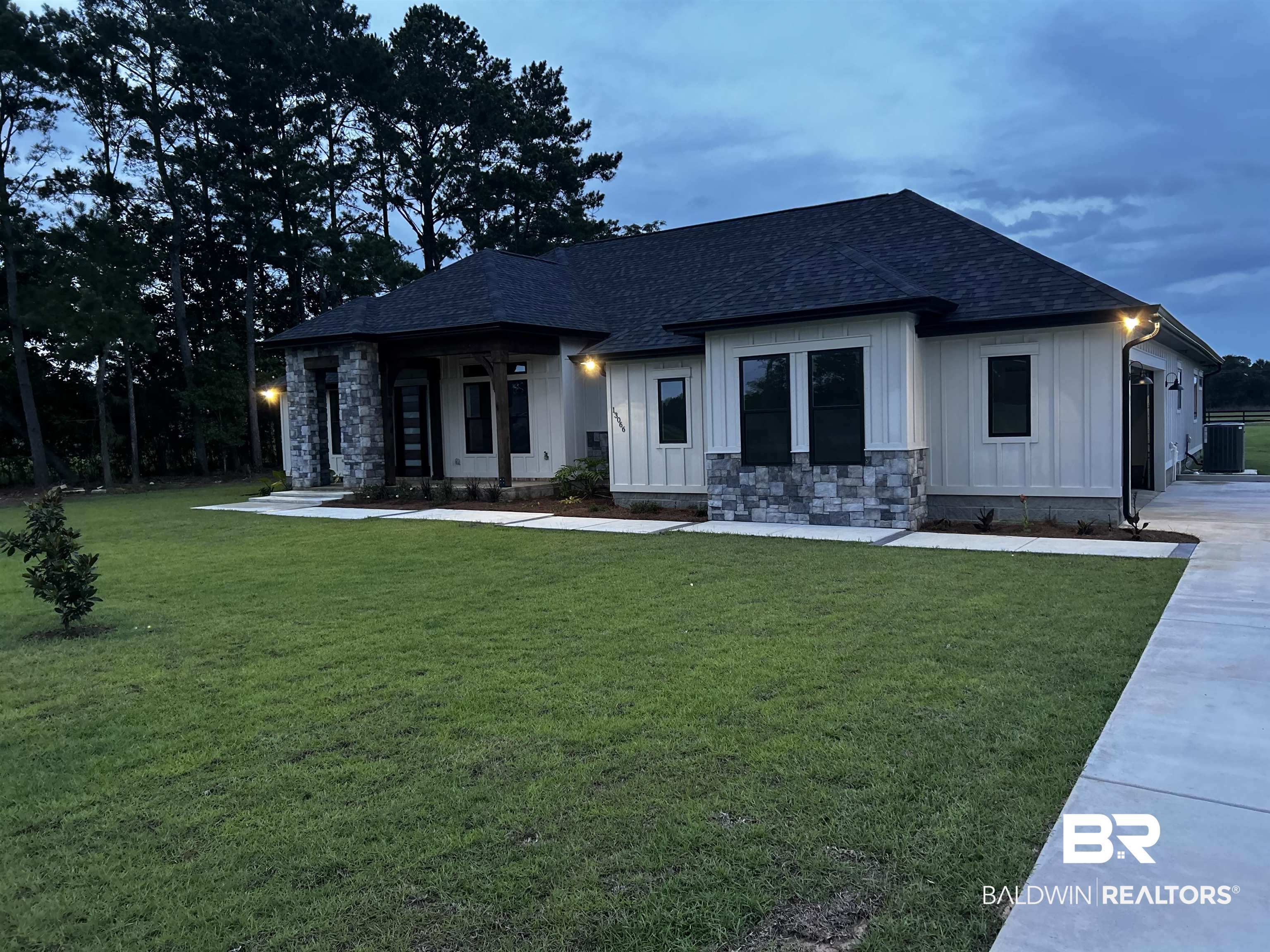 13066 Gopher Court Elberta, AL 36530 - Photo 31 of 38 Contemporary-style residence featuring a dark asphalt shingle roof, board and batten vertical siding, and grey stone accents.