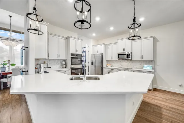 a large kitchen with kitchen island a stove a sink a center island and wooden floor