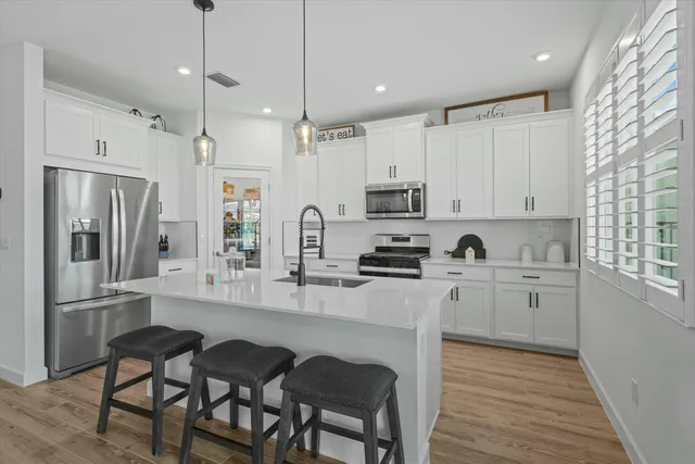 a kitchen with appliances a sink cabinets and a wooden floor