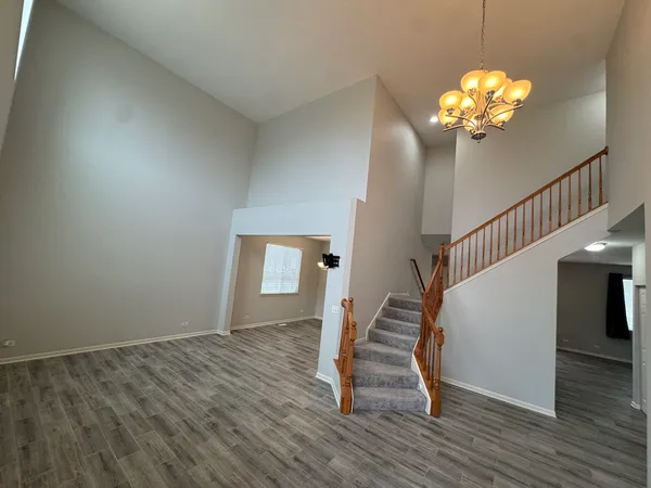 a view of an empty room with wooden floor fireplace and a window
