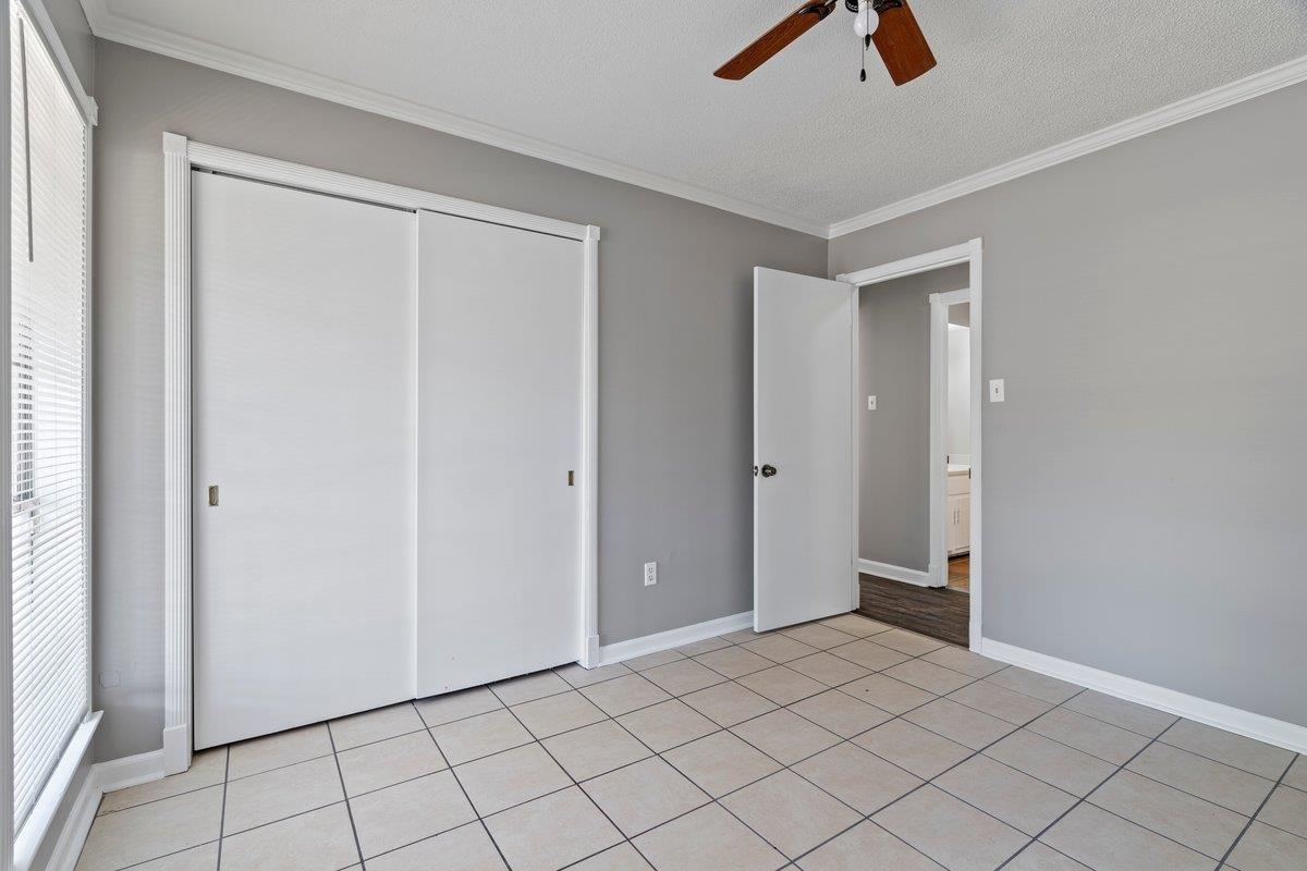 3384 South Mendenhall Road Memphis, TN 38115 - Photo 11 of 22 Unfurnished bedroom with ceiling fan, crown molding, light tile patterned flooring, and a closet