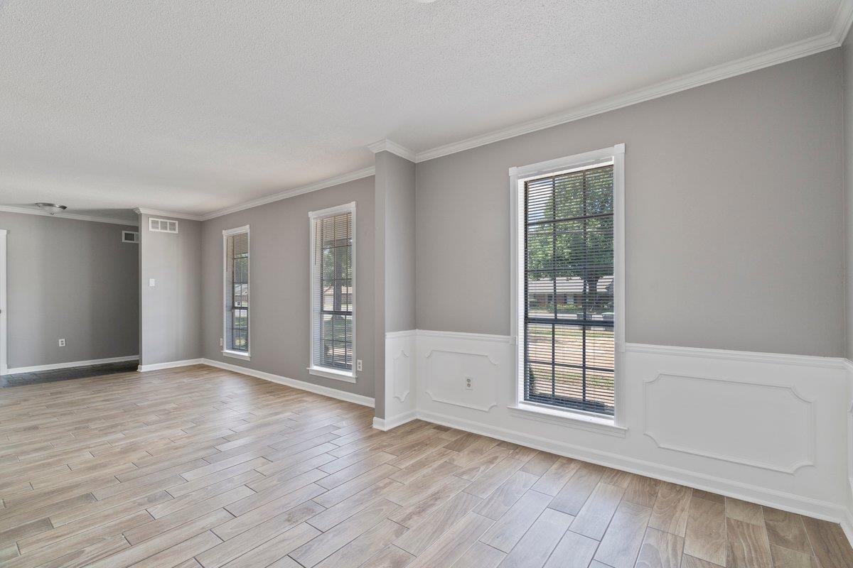 Empty room with light hardwood / wood-style floors, ornamental molding, and a textured ceiling