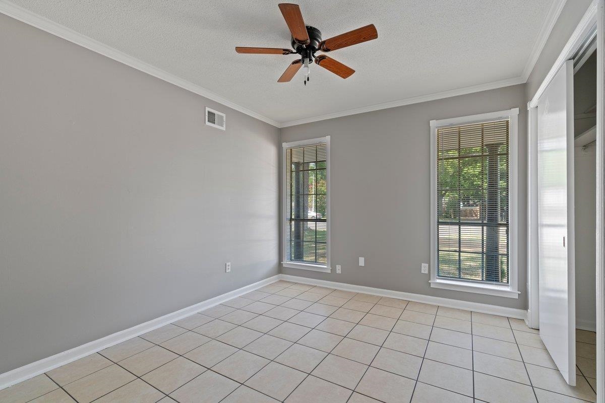 3384 South Mendenhall Road Memphis, TN 38115 - Photo 9 of 22 Tiled empty room featuring ceiling fan, plenty of natural light, and crown molding