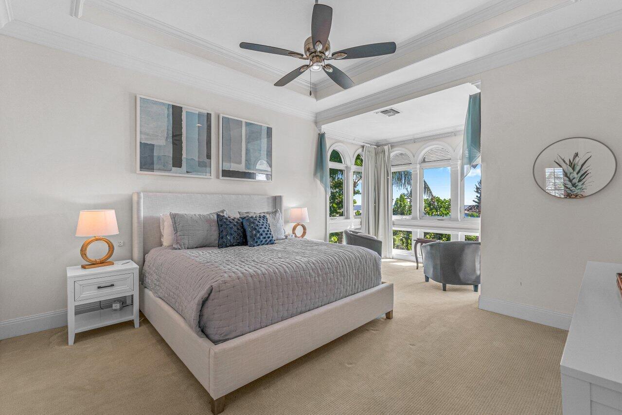 6103 North Ocean Boulevard Ocean Ridge, FL 33435 - Photo 27 of 53 a spacious bedroom with a bed a chandelier and a window