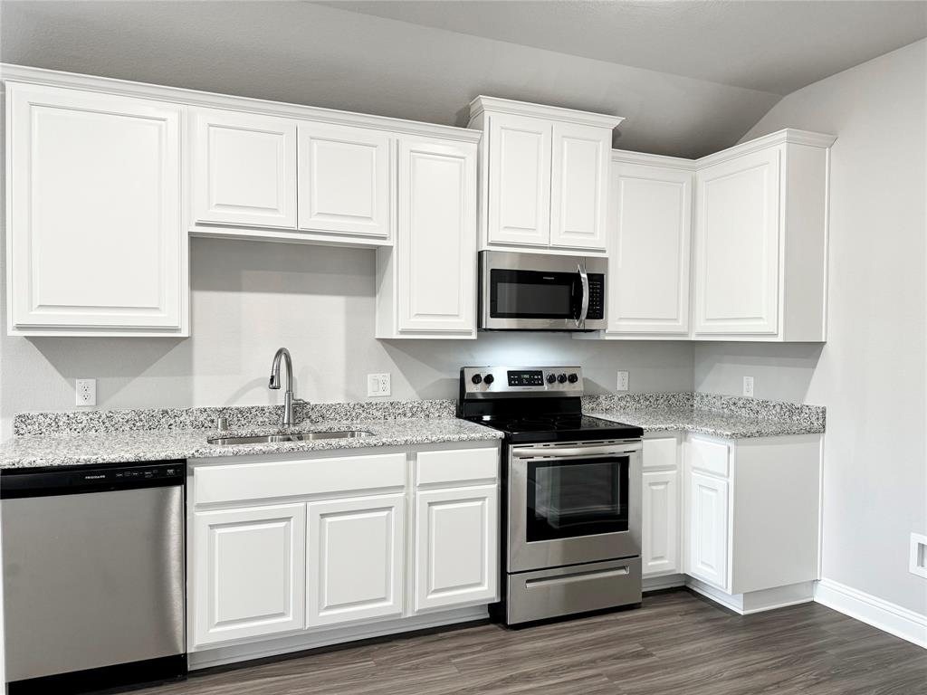 6408 Rienzi Drive Greenville, TX 75402 - Photo 3 of 20 a kitchen with stainless steel appliances granite countertop white cabinets and a wooden floor