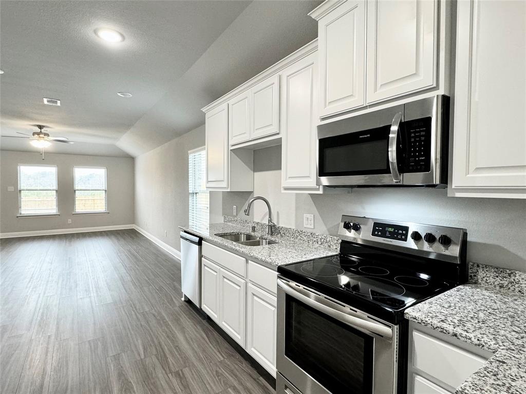 6408 Rienzi Drive Greenville, TX 75402 - Photo 4 of 20 a kitchen with stainless steel appliances kitchen island granite countertop a stove a sink dishwasher and a microwave oven with white cabinets