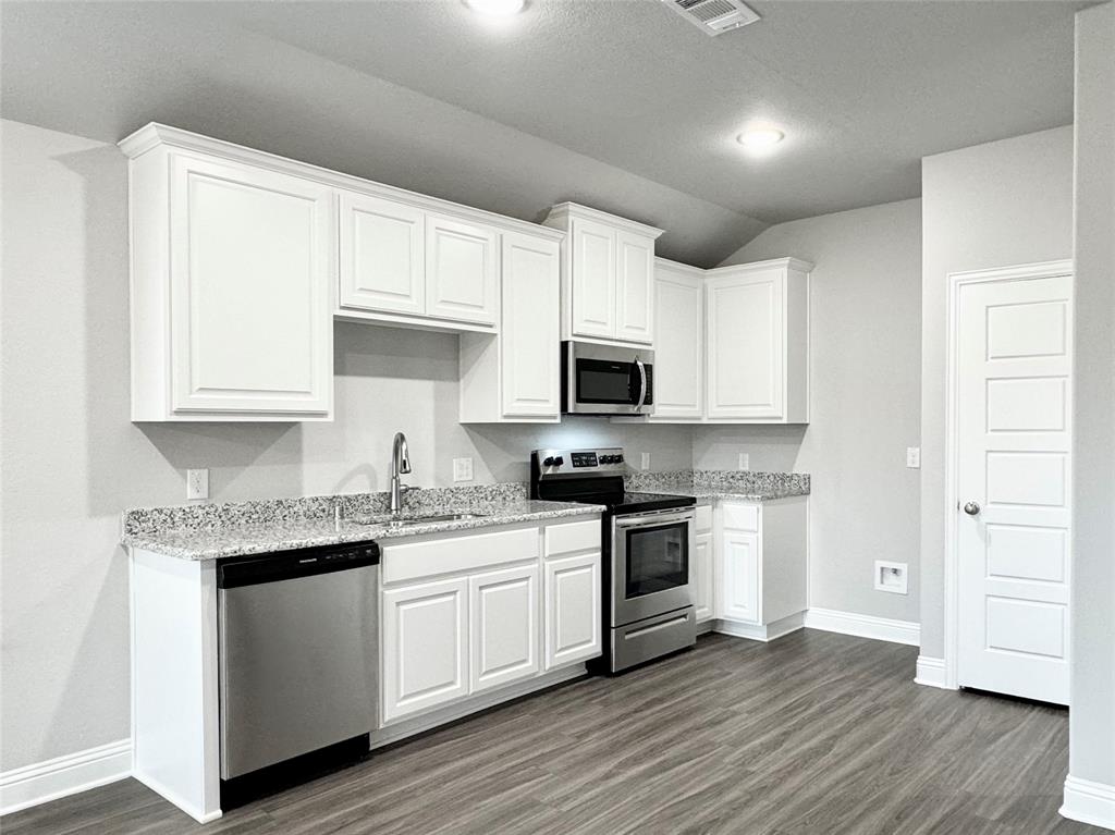 6408 Rienzi Drive Greenville, TX 75402 - Photo 5 of 20 a kitchen with stainless steel appliances granite countertop white cabinets a sink a stove a microwave and cabinetry