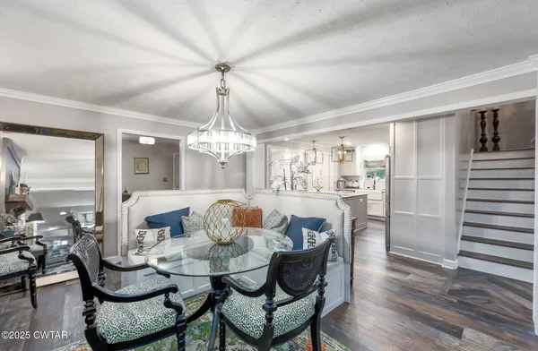 a dining room with wooden floor a chandelier a wooden table and chairs