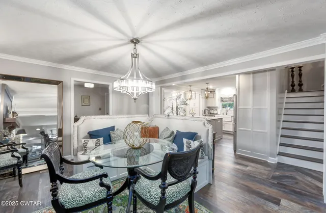 a dining room with wooden floor a chandelier a wooden table and chairs