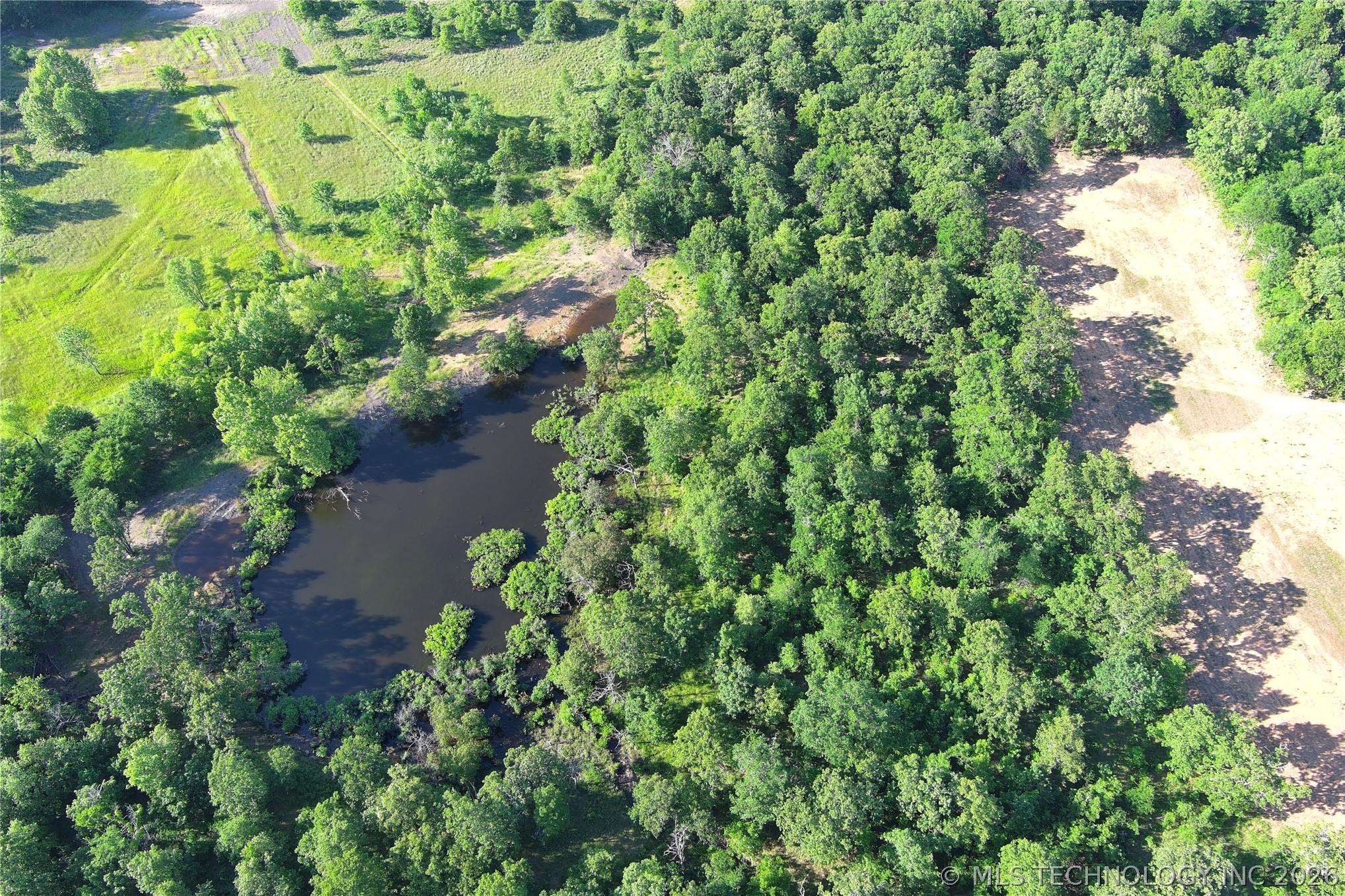 20862 East 1160th Road Keota, OK 74941 - Photo 4 of 47 Expansive wooded acreage featuring a large pond, open cleared areas, and dense tree coverage