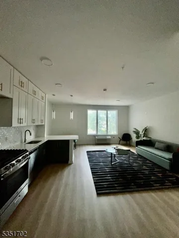 a living room with stainless steel appliances furniture a window and a kitchen view