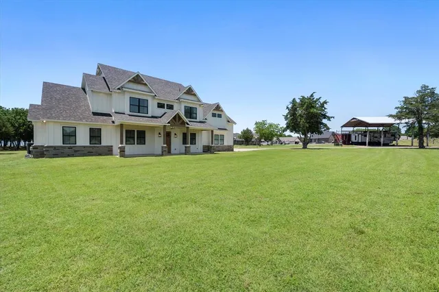 a view of a house with a big yard and large trees