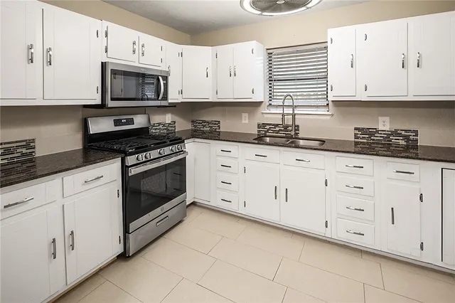 a kitchen with stainless steel appliances granite countertop grey cabinets a stove a sink and dishwasher