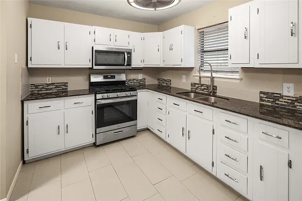 a kitchen with granite countertop white cabinets and stainless steel appliances