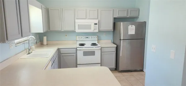a kitchen with white cabinets and white appliances