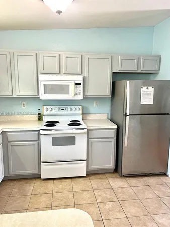 a kitchen with a stove top oven cabinets and a refrigerator