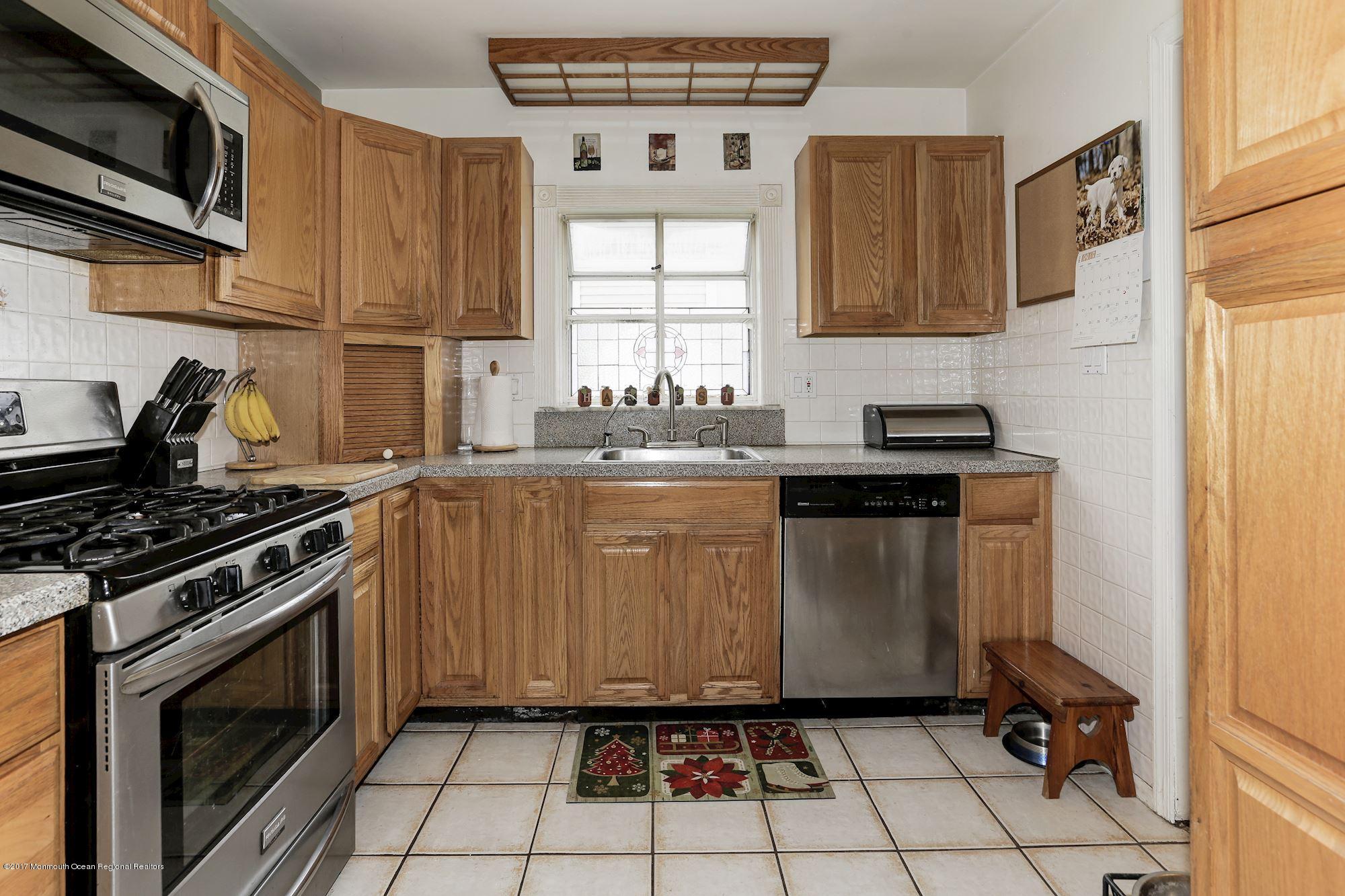 27 Long Road Freehold, NJ 07728 - Photo 6 of 25 a kitchen with a stove a sink and a microwave