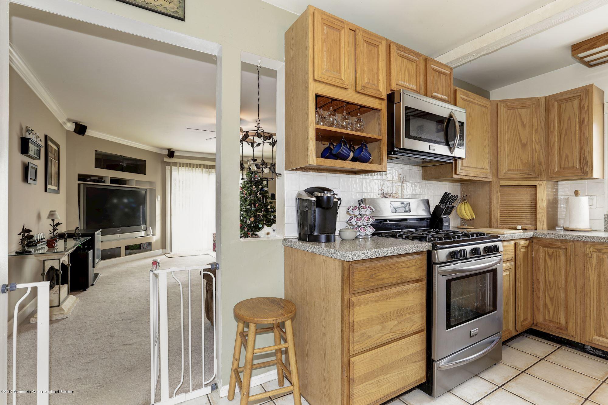 27 Long Road Freehold, NJ 07728 - Photo 7 of 25 a kitchen with stainless steel appliances granite countertop a stove top oven a sink a refrigerator and white cabinets with wooden floor