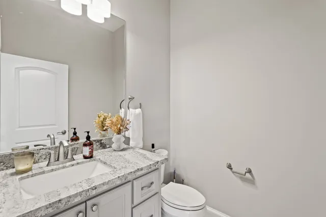 a bathroom with a granite countertop sink mirror vanity and toilet