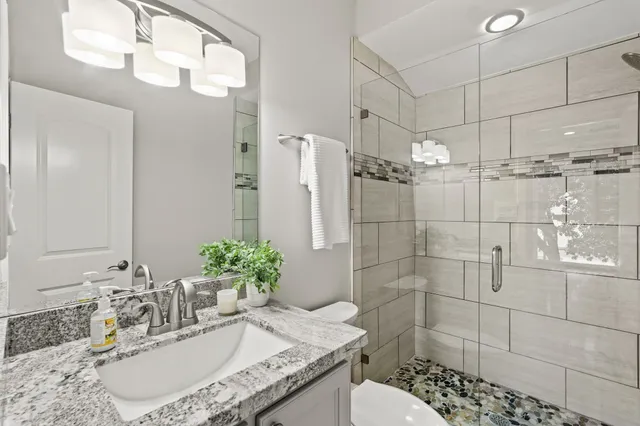 a bathroom with a granite countertop sink a toilet and shower