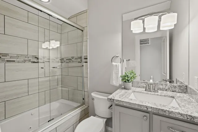 a bathroom with a granite countertop sink a toilet and shower