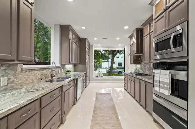 a large kitchen with stainless steel appliances granite countertop a stove and a sink