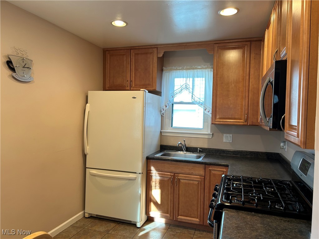 1094 Plainfield Road Cleveland, OH 44121 - Photo 4 of 41 Kitchen featuring sink, light tile patterned floors, black gas range oven, and white refrigerator