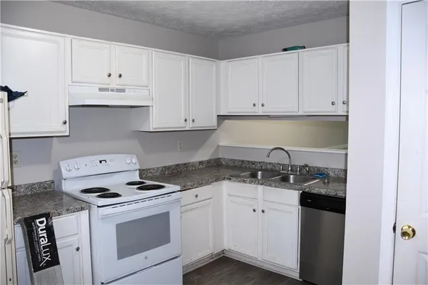 a kitchen with granite countertop white cabinets and white appliances