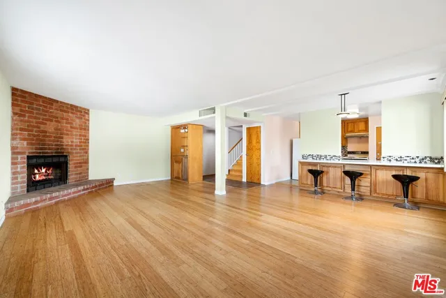 a view of an empty room with kitchen and a fireplace