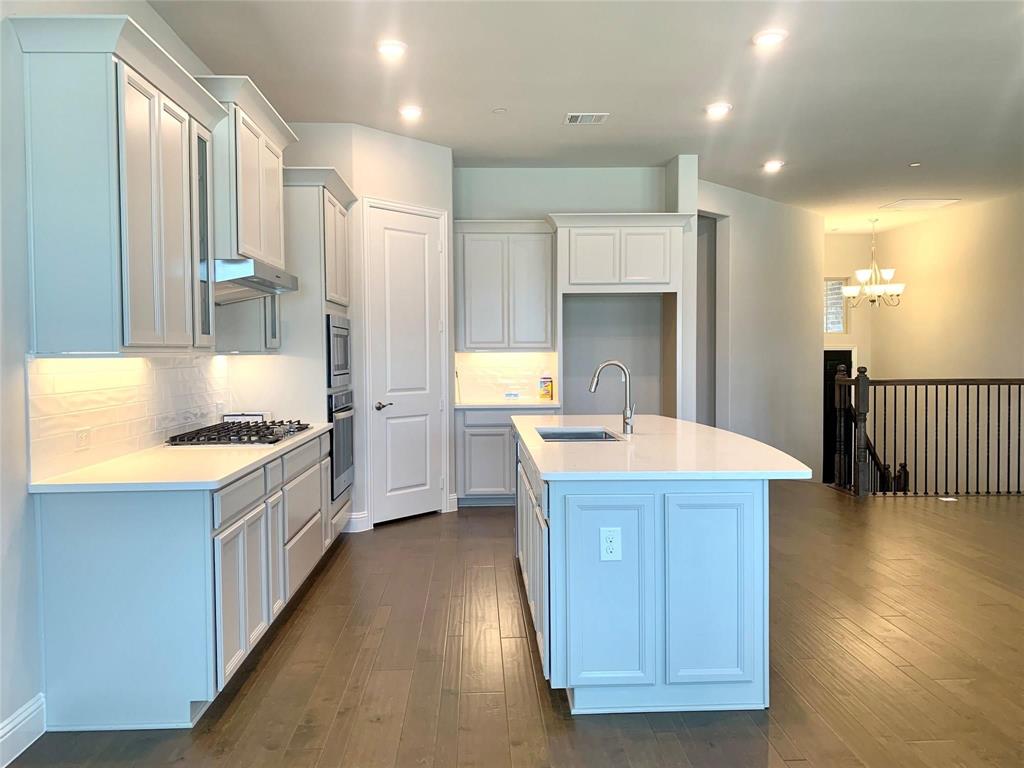 5537 Yellowstone Road The Colony, TX 75056 - Photo 5 of 25 Kitchen with backsplash, dark wood finished floors, light stone counters, an island with sink, and recessed lighting