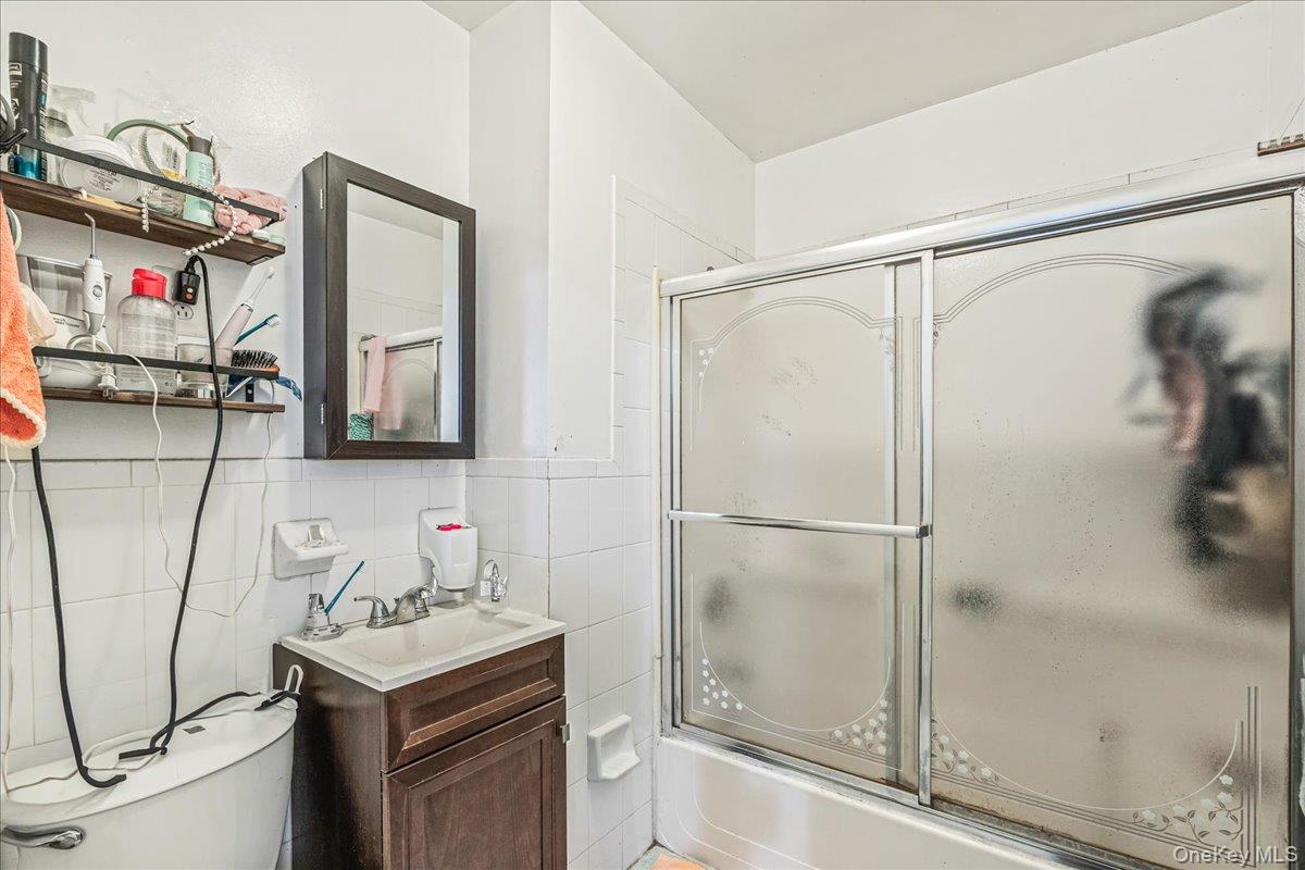 34-49 110th Street Queens, NY 11368 - Photo 11 of 21 a bathroom with a shower sink vanity and mirror