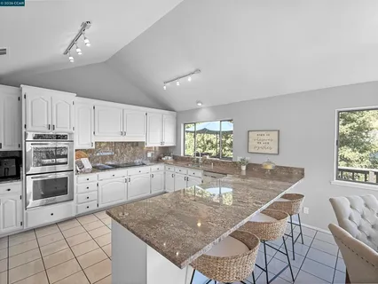 a kitchen with kitchen island granite countertop a stove a sink a counter space and cabinets